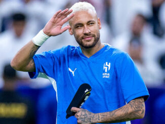 Joueur de football saluant en maillot bleu.