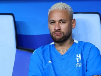 Joueur de football en tenue bleue, assis, sérieux.