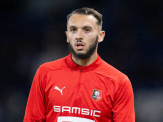 Joueur de football en maillot rouge sur le terrain.