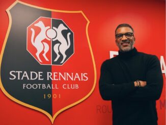 Homme devant logo du Stade Rennais Football Club.