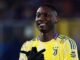 Joueur de football en maillot jaune souriant.