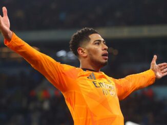 Footballeur en maillot orange célébrant un but.