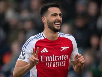 Joueur de football souriant en maillot rouge.