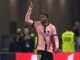 Joueur de football levant le bras sur le terrain.