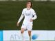 Joueur de football en tenue blanche sur le terrain.