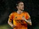 Joueur de football sous la pluie, en maillot orange.