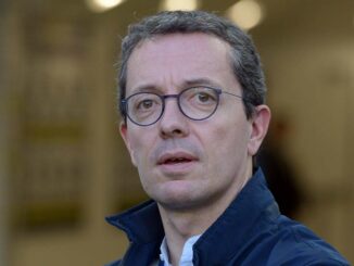 Homme avec lunettes et veste bleu.
