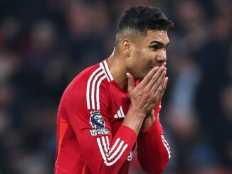 Footballeur en maillot rouge mains jointes.