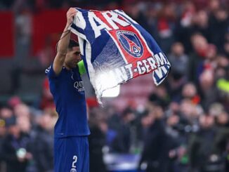Joueur tenant drapeau PSG sur le terrain.