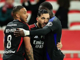 Trois footballeurs s'embrassent après un match.