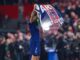 Joueur de football tenant drapeau du PSG.