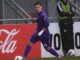 Joueur de football dribble en tenue violette.