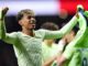 Joueur de football joyeux brandissant un maillot vert.