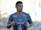 Footballeur en maillot gris sur le terrain.