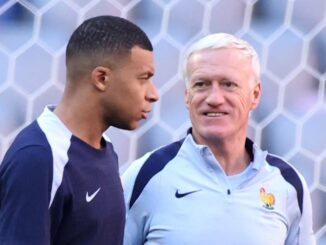 Deux hommes discutent devant filet de football.