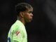 Joueur de football en profil sur fond sombre.