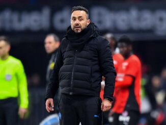 Homme en manteau noir sur le terrain de football.