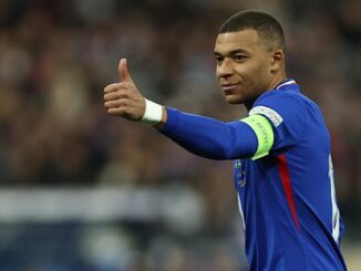 Joueur de football en maillot bleu fait un pouce.