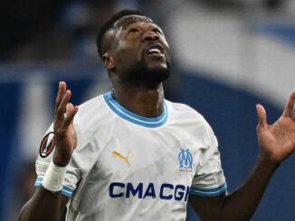 Joueur de football en maillot blanc regarde vers le ciel.