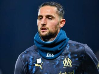 Footballeur en maillot de l'OM sur le terrain.