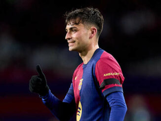 Footballeur en maillot bleu et rouge avec pouce levé.