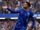 Joueur de football célébrant sous la pluie à Londres.
