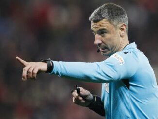 Arbitre de football pointant du doigt en match.