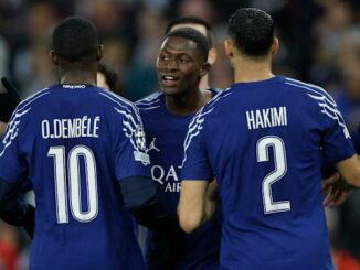 Joueurs de football en maillots bleus discutant sur le terrain.