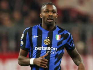 Footballeur en maillot bleu et noir sur le terrain.