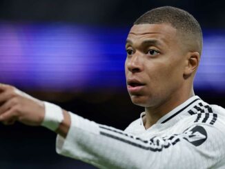 Footballeur en maillot blanc pointant du doigt.