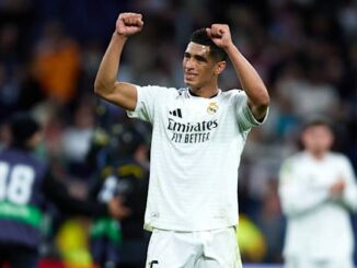 Joueur de football levant les bras vers le public.
