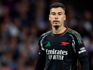 Joueur de football en maillot noir sur le terrain.