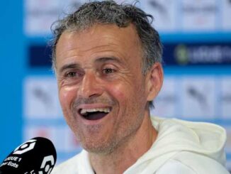 Homme souriant lors d'une conférence de presse.