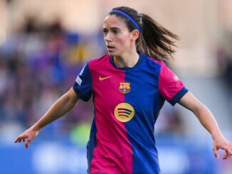 Footballeuse en action, maillot rose et bleu.