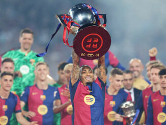 Joueur de football levant un trophée argenté.