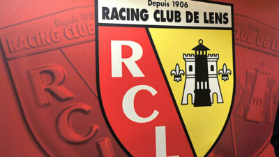 Logo Racing Club de Lens sur mur rouge.
