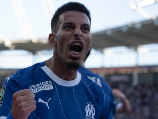 Joueur de foot célébrant un but dans un stade.