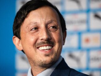 Homme souriant devant un fond publicitaire.