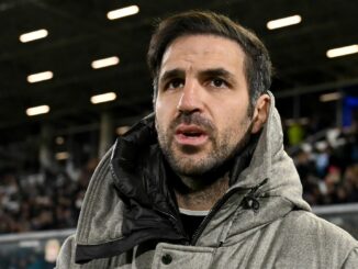 Homme en manteau dans un stade bondé.