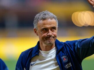 Homme en veste PSG levant la main.