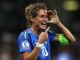 Joueuse de football souriante sur le terrain.