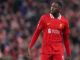 Joueur en maillot de football rouge sur le terrain.