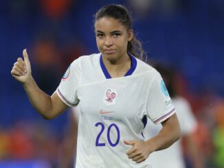 Joueuse de football en maillot blanc, pouce levé.