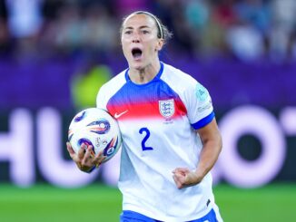 Footballeuse portant un ballon sur le terrain.