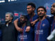 Joueurs de football en maillot PSG bras dessus-dessous.