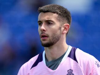 Homme en maillot de sport rose sur fond bleu.