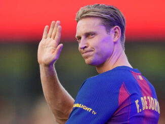 Footballeur saluant en tenue bleue et rouge.