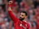 Joueur de football célébrant en maillot rouge.