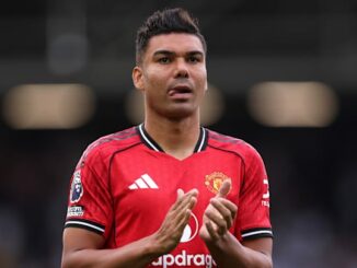 Joueur de football applaudissant en maillot rouge.