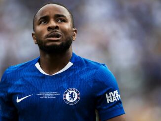 Joueur de football en maillot bleu, regard déterminé.